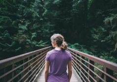 אישה חוצה גשר עץ בשמורת טבע