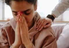 אישה אוחזת את שתי ידיה בסמוך לפניה בתנוחת תפילה