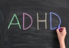 כף יד כותבת את המילה ADHD באנגלית בגירים ציבעוניים