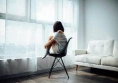 ילדה בדיכאון יושבת על כסא ליד החלון