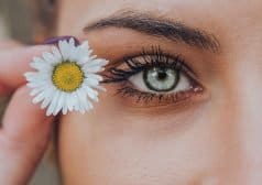 אישה אוחזת בפרח בסמוך לעין